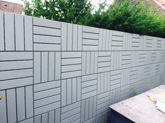 an outdoor table and bench in front of a wall made out of cinder block blocks