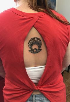 the back of a woman's red shirt with a tattoo on her left shoulder