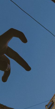 a kite is flying high in the sky above some buildings and power lines, with a blue sky behind it