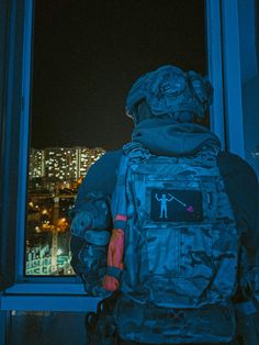 a man standing in front of a window with his back to the camera and looking out