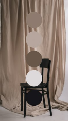 a chair sitting in front of a curtain with three circles hanging from it's back