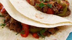 two tacos with meat, peppers and onions