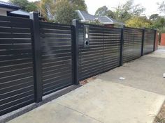 a black metal fence next to a sidewalk