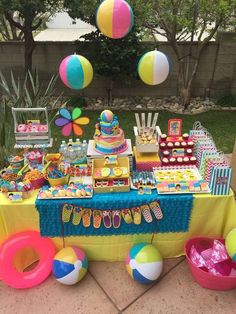 the table is set up for a pool party with beach ball decorations and candy bars