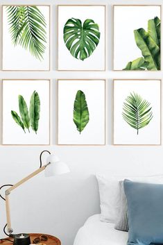 four green leaf prints hanging on the wall above a bed