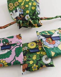 three small pouches with flowers and leaves on them, one has a name tag attached to it