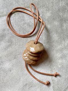 "Simplicity and repose are qualities that measure the true value of any work of art..." So said Frank Lloyd Wright, and who are we to argue with that notorious crank? Anyway. We love the repose of this necklace by Elise Birnbaum of Oatmeal Ceramics. The elements: ceramic and and leather. The form: simplicity itself. Cairns to mark the way on your path. This may be statement piece in scale, but there’s a subtlety in its refined restraint. Simplicity and repose indeed. 1.5" pendant on a 40" leather cord. Earthy Adjustable Round Pendant Necklace, Earthy Adjustable Round Necklace, Adjustable Earthy Pendant Necklaces, Artisan Round Pendant Necklace For Everyday, Adjustable Large Pendant Necklace For Everyday, Adjustable Everyday Necklace With Large Pendant, Everyday Adjustable Necklace With Large Pendant, Artistic Adjustable Brown Necklace, Adjustable Brown Artistic Necklace