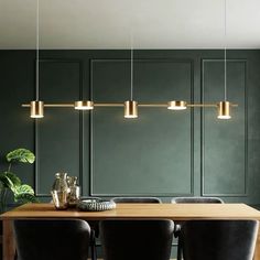 a dining room table with black chairs and gold lights hanging from the ceiling over it