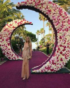 a woman is standing in front of a flowered circle at the entrance to an event