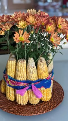 an arrangement of corn on the cob with colorful flowers in it and ribbons tied around them