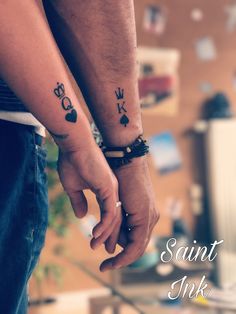 two people holding hands with tattoos on their arms and the words saint nick written in black ink