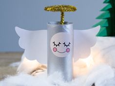 a tin can with an angel sticker on it sitting next to a christmas tree