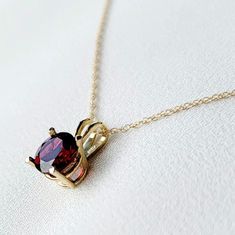 A stunning red garnet necklace, crafted with exquisite detail, featuring a rich and vibrant garnet pendant as the focal point. The deep red gemstone is elegantly set in a fine metal setting of your choice, complemented by a delicate chain. This timeless piece adds a touch of sophistication and warmth to any attire, making it a perfect accessory for both casual and formal occasions. These necklaces are available in your choice of a 14k solid gold setting (yellow or rose gold), or .925 solid silve Elegant Oval Garnet Necklace, Red Garnet Oval Pendant Necklace, Yellow Gold Garnet Necklaces With Oval Shape, Yellow Gold Oval Garnet Necklace, Oval Garnet Necklaces For Anniversary, Oval Garnet Necklace For Anniversary, Formal Yellow Gold Garnet Necklaces, Formal Yellow Gold Garnet Necklace, Fine Jewelry Yellow Gold Garnet Necklaces