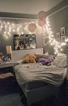 a bedroom with lights strung from the ceiling and stuffed animals on the bed in front of it