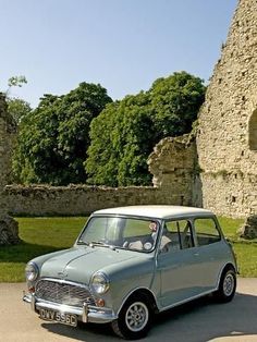 an old mini car parked in front of a castle