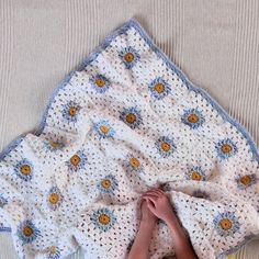 a person is laying down under a crocheted blanket on the floor with their hands