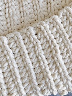 the texture of a blanket is white and has braided edges, as well as an interlocking pattern