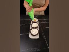 a woman is decorating a cake with green icing