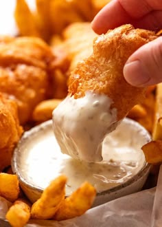 a person dipping some kind of food into a bowl with chips and dip in it