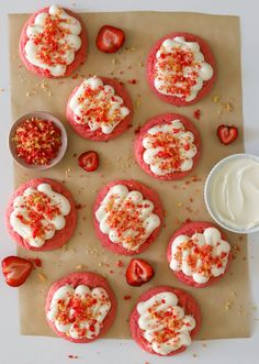 strawberry shortcakes with whipped cream and sprinkles on a piece of parchment paper