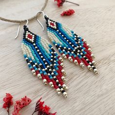 a pair of beaded earrings with red, white and blue beads hanging from a string