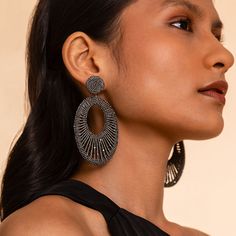 a woman wearing large earrings and black dress