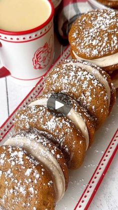 some pastries are sitting on a red and white plate next to two cups of coffee