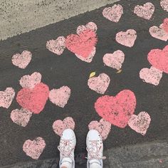 someone is standing on the sidewalk with hearts painted on it