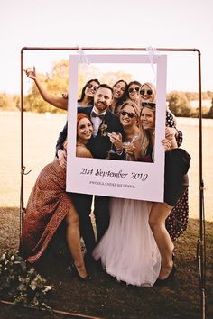 a group of people standing next to each other in front of a white sign with a photo on it