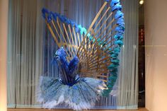 a blue and white peacock sculpture sitting on top of a table next to a window