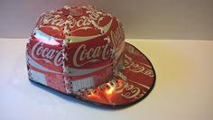 a coca - cola light up hat sits on top of a white table with lights