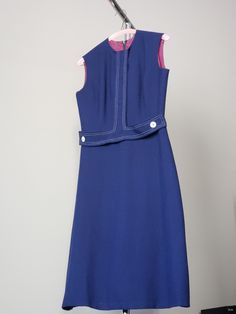 a blue dress hanging on a clothes rack with a pair of scissors in the background