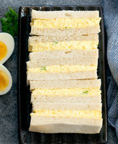 eggs and bread on a black tray next to an egg shell, with two halves cut in half