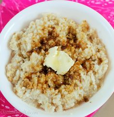 a white bowl filled with oatmeal and butter on top of a pink table cloth