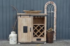 an old wooden cabinet sitting next to a metal fence with a wine rack on top