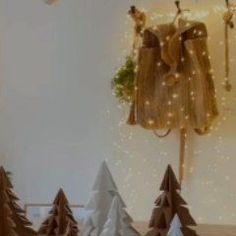 there are many small christmas trees on the table and one is hanging from the wall