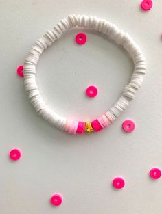 a pink and white beaded bracelet sitting on top of a table next to sprinkles