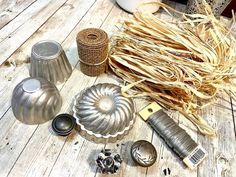 various metal items sitting on top of a wooden table next to a vase and brush