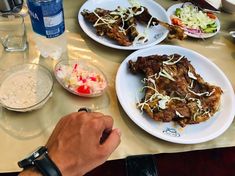 a person is sitting at a table with plates of food