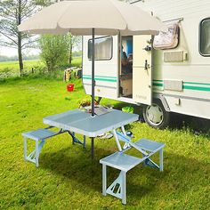 an rv parked in the grass next to a picnic table with an umbrella over it