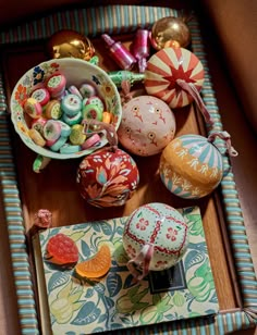 an assortment of colorfully decorated eggs and candies on a tray with striped cloth