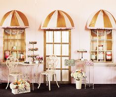 a room filled with white chairs and tables in front of two windows covered in pink curtains