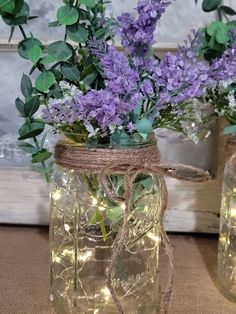 two mason jars filled with purple flowers and string lights