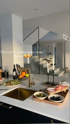 an image of a kitchen setting with food on the counter and wine glasses in the sink