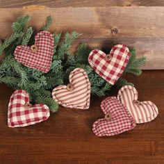 red and white checkered heart ornaments sitting on top of a wooden table next to pine branches