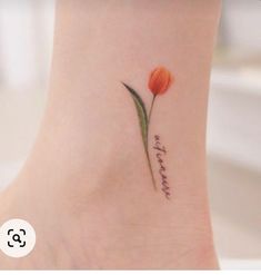 a small tattoo on the ankle with a single flower and words written in cursive writing