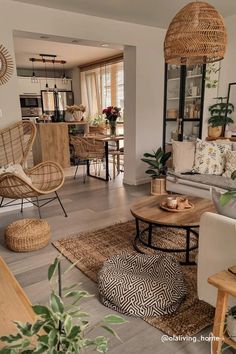 a living room filled with lots of furniture and plants on top of wooden flooring