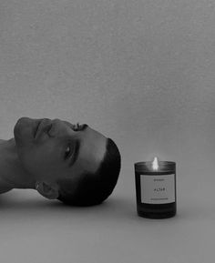 a man laying on the ground next to a candle