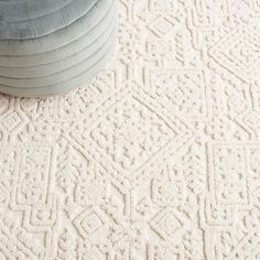 a white rug on the floor next to a blue round chair and footstool