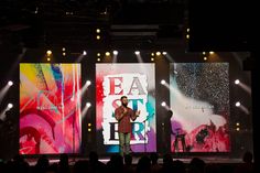 a man standing on top of a stage in front of two large screens with words